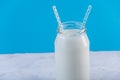 Glass bottle of fresh milk with two straws on blue background. Colorful minimalism. Healthy dairy products Royalty Free Stock Photo