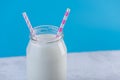 Glass bottle of fresh milk with two straws on blue background. Colorful minimalism. Healthy dairy products Royalty Free Stock Photo