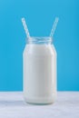 Glass bottle of fresh milk with two straws on blue background. Colorful minimalism. Healthy dairy products Royalty Free Stock Photo