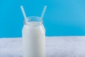 Glass bottle of fresh milk with two straws on blue background. Colorful minimalism. Healthy dairy products Royalty Free Stock Photo