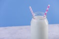 Glass bottle of fresh milk with two straws on blue background. Colorful minimalism. Healthy dairy products Royalty Free Stock Photo