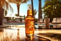 A glass bottle of fresh open beer on a wooden table outdoors. Swimming pool, sun beds and palm trees in the background. Generated