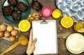 Glass bottle of fresh orange juice with fresh fruits and almond, hazelnuts and homemade chocolate muffins and flour, hand woman ho