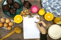 Glass bottle of fresh orange juice with fresh fruits and almond, hazelnuts and homemade chocolate muffins and flour, hand writing