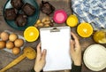 Glass bottle of fresh orange juice with fresh fruits and almond, hazelnuts and homemade chocolate muffins and flour, hands woman h