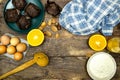 Glass bottle of fresh orange juice with fresh fruits and almond, hazelnuts and homemade chocolate muffins and flour on wooden tabl