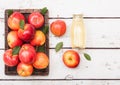 Glass bottle of fresh organic apple juice with pink lady red apples in vintage box on wooden background Royalty Free Stock Photo