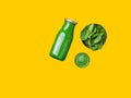 Glass bottle with fresh raw spinach leafy greens vegetables fruits smoothie on yellow background. Healthy plant based diet Royalty Free Stock Photo