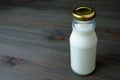 Glass Bottle full of milk isolated on dark colored wooden table with copy space