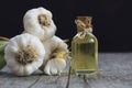 Glass bottle of garlic oil and Ripe and fresh garlic plant on wooden or rustic table