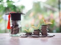 Glass bottle with graduation hat and Plants growing up on stack of coins. The concept of saving money for education, student loan Royalty Free Stock Photo