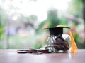 Glass bottle with graduation hat and stack of coins. The concept of saving money for education, student loan, scholarship, tuition Royalty Free Stock Photo