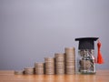 Glass bottle with graduation hat and stack of coins. The concept of saving money for education, student loan, scholarship, tuition Royalty Free Stock Photo