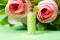 Glass bottle with green granules and roses in the background. homeopathic remedies Royalty Free Stock Photo