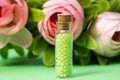 glass bottle with green granules and roses in the background. homeopathic remedies Royalty Free Stock Photo