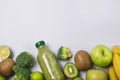 Glass Bottle of Green Healthy Smoothie with Banana Broccoli Green Apples Lime and Kiwi Blue Background Above Horizontal Copy Space