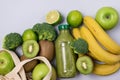 Glass Bottle of Green Healthy Smoothie with Banana Broccoli Green Apples Lime and Kiwi Blue Background Above Horizontal