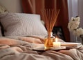 A glass bottle of home perfume stands adorned with wooden sticks, emanating a soothing fragrance. Scented candles emit