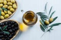 Glass bottle of homemade olive oil and olive tree branch, raw turkish green and black olive seeds and leaves on white table Royalty Free Stock Photo