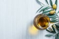 Glass bottle of homemade olive oil and olive tree branch, raw turkish green olive seeds and leaves on white table Royalty Free Stock Photo