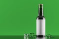 Glass bottle with ice cubes over green background Royalty Free Stock Photo