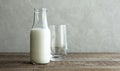 A glass bottle with kefir, milk or homemade fresh yogurt stands on a rustic table and next to it is an empty glass cup. Kefir is a