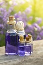 Glass bottle of Lavender essential oil on wood table and flowers field. Lavendula oleum