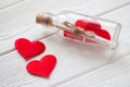 Glass bottle with letter and red hearts on a white wooden background. The concept of Valentine's Day. Close-up. Royalty Free Stock Photo