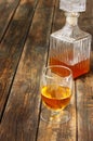 Glass and bottle of liquor like scotch, bourbon, whiskey or brandy on wooden table