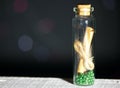 Glass bottle with a note inside. A note in the form of rolled up paper bound in a rope. Beads are poured at the bottom of the