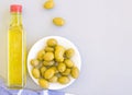 A glass bottle of olive oil, a bowl of olives, and a towel. Grey background, space for text. Royalty Free Stock Photo