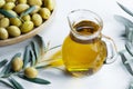 Glass bottle of olive oil and olive tree branch, raw turkish green olive seeds Royalty Free Stock Photo