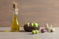Glass bottle of olive oil and wooden breakfast bowl with raw turkish olive seeds and leaves on wooden rustic vintage table. Olives Royalty Free Stock Photo