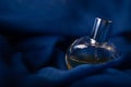 Glass bottle of perfume on dark blue mysterious romantic background. Concept of scents and smells close-up macro studio shot