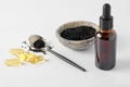 Glass bottle and pills of black cumin seeds essential oil. Nigella Sativa in spoon and bowl on white background Royalty Free Stock Photo
