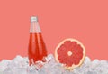 Glass bottle of pink grapefruit drink on ice Royalty Free Stock Photo