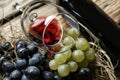 Glass and bottle of red wine with fresh grapes on wooden table Royalty Free Stock Photo