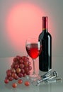 Glass and bottle with red wine, grapes and corkscrew on colored background Royalty Free Stock Photo