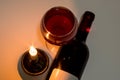 A glass and a bottle of red wine next to a burning candle Royalty Free Stock Photo