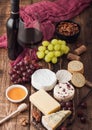 Glass and bottle of red wine with selection of various cheese on the board and grapes on wooden background. Blue Stilton, Red Royalty Free Stock Photo