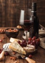 Glass and bottle of red wine with selection of various cheese on the board and grapes on wooden background. Blue Stilton, Red Royalty Free Stock Photo