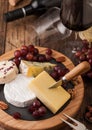 Glass and bottle of red wine with selection of various cheese on the board and grapes on wooden background. Blue Stilton  Red Royalty Free Stock Photo