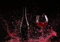 Glass and bottle of red wine splash on black Royalty Free Stock Photo