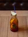 A glass bottle with a refreshing cool beverage, a slice of fragrant lime on a blurred wooden background. Royalty Free Stock Photo