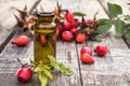 Glass bottle of rosehip seed essential oil with fresh fruits on a wooden table. Tincture or essential oil with rose hips Royalty Free Stock Photo