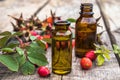 Glass bottle of rosehip seed essential oil with fresh fruits on a wooden table. Tincture or essential oil with rose hips Royalty Free Stock Photo