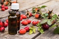 Glass bottle of rosehip seed essential oil with fresh fruits on a wooden table. Tincture or essential oil with rose hips Royalty Free Stock Photo