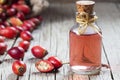 Glass bottle of rosehip seed essential oil with fresh rose hip fruits on wooden rustic background