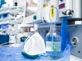 A glass bottle with saline and a white medical mask on the table in the hospital.