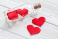 Glass bottle with satin red hearts on a white wooden background. The concept of Valentine's Day. Close-up. Royalty Free Stock Photo